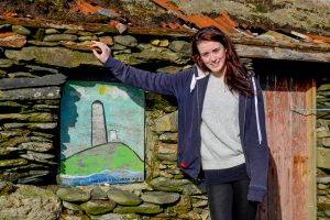 Carina O'Halloran (19years old) with the painting she painted as an 8 year old durinf an Art Project run by artist Lol Hardman from Clifden. The artworks all painted by children from the island were installed into ruined buildings to brighten up the villages. Inishbofin, Co Galway, Ireland.
